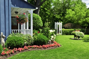 Благоустроенный двор дома с цветами и зеленым газоном