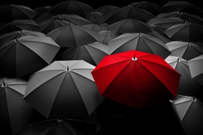 Бизнес-концепция лидера. Красный зонт выделен среди черных