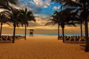 Закат на пляже с пальмами и лежаками