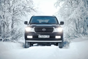 Черный внедорожник Toyota LandCruiser в заснеженном лесу