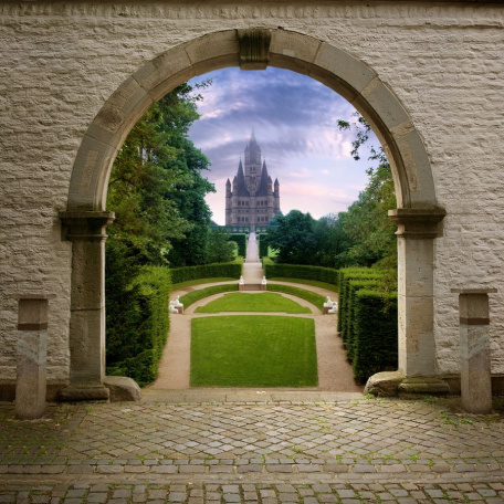 Вид на замок через арку в саду