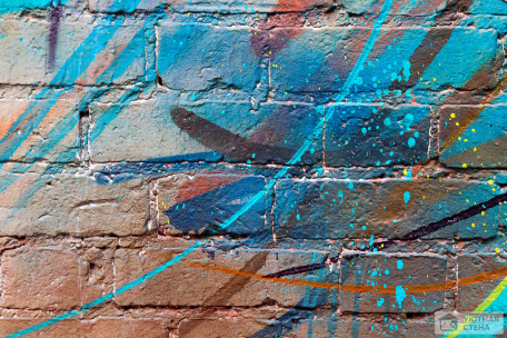 Голубое граффити на коричневой кирпичной стене