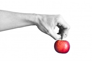 Черно белая рука держит красное яблоко