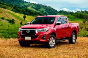 Красная Toyota Hilux на фоне зеленой горы