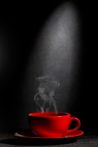 Красная чашка горячего кофе на черном фоне