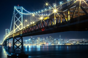 Мост с яркими фонарями на фоне мегаполиса ночью