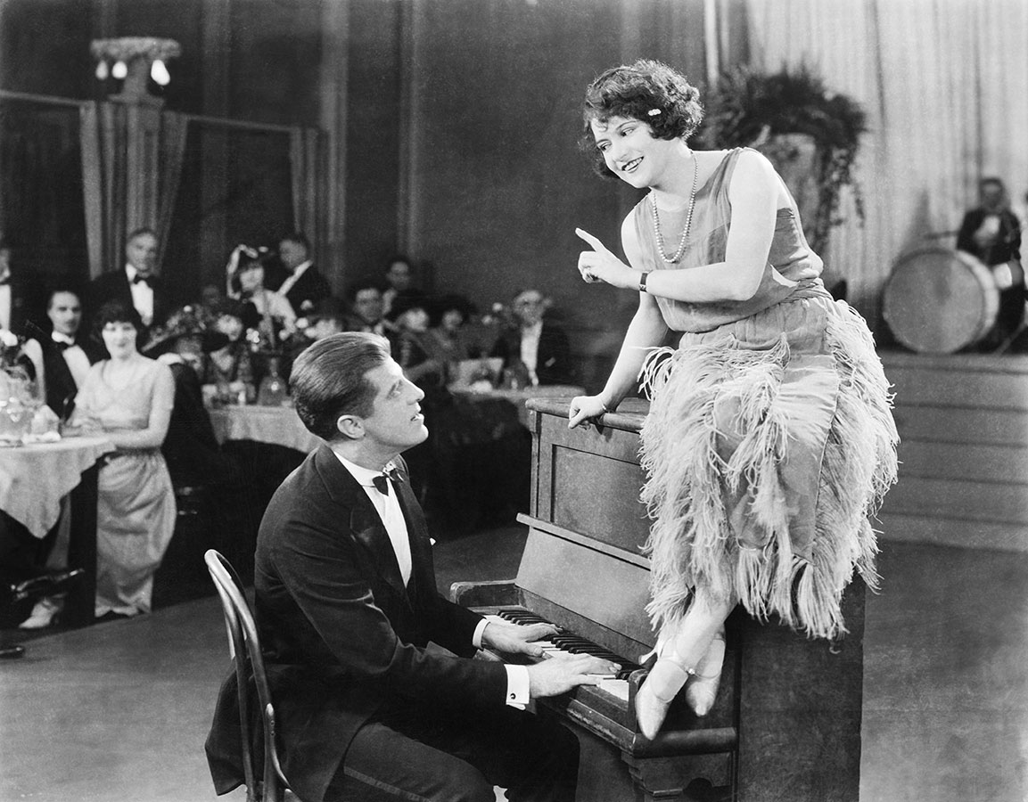 Woman sitting on a nightclub piano, 1920s