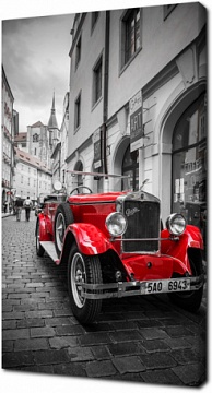 Красный ретро автомобиль на фоне черно-белой Праги