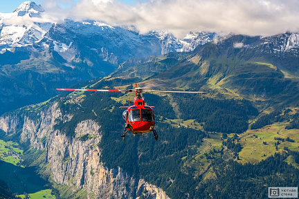 Красный вертолет летит в горах