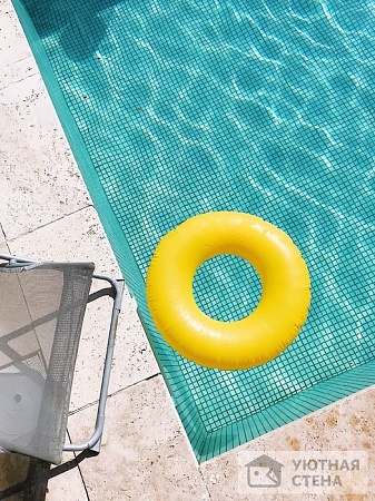 Яркий спасательный круг в голубой воде бассейна