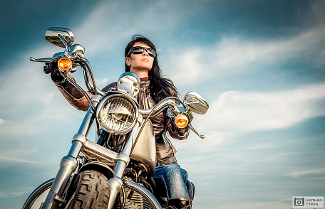 Байкер девушка в кожаной куртке на мотоцикле