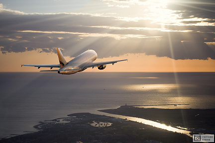 Фото самолета, летящего над морем на закате