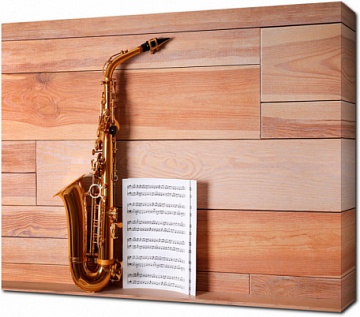 Саксофон и нотные листы на деревянном фоне