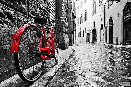 Винтажный красный велосипед на мощеной улочке