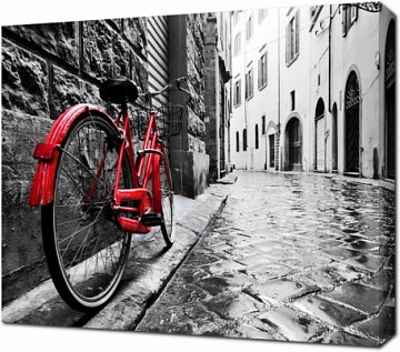 Винтажный красный велосипед на мощеной улочке