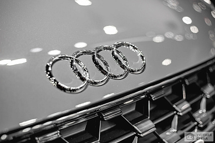 Логотип на передней части автомобиля Audi цвета металлик