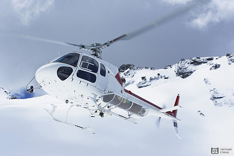 Вертолет летит над снежными горными вершинами